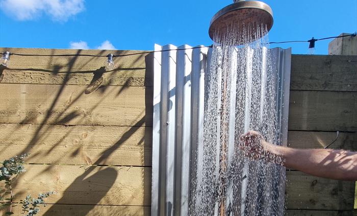 An outdoor shower raining down water against a blue sky